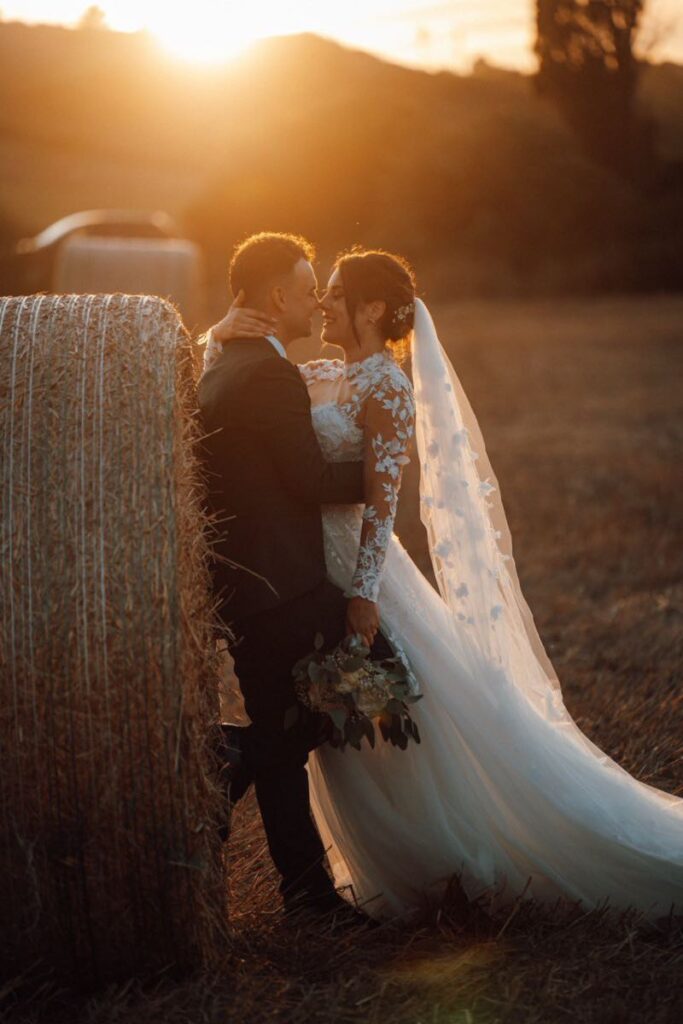 Sposi al tramonto in un campo di fieno