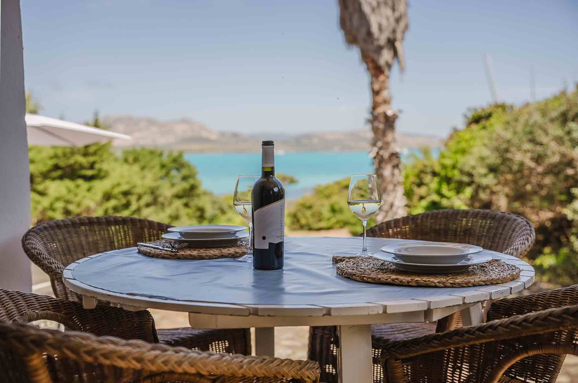 Casa vacanze in Sardegna con giardino e tavolo in legno apparecchiato con piatti e bottiglia di vino