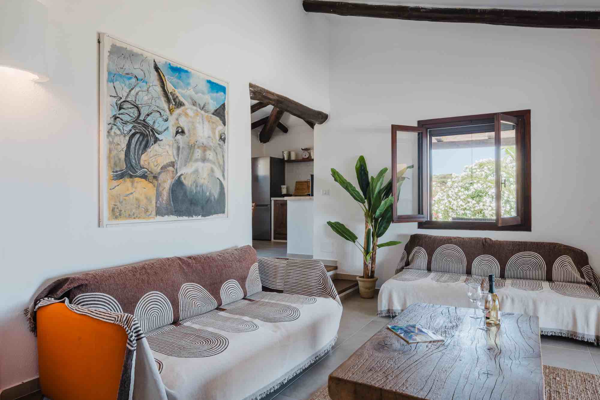 Salotto di una casa vacanze in Sardegna con dipinto di un asino e arredamento in stile sardo