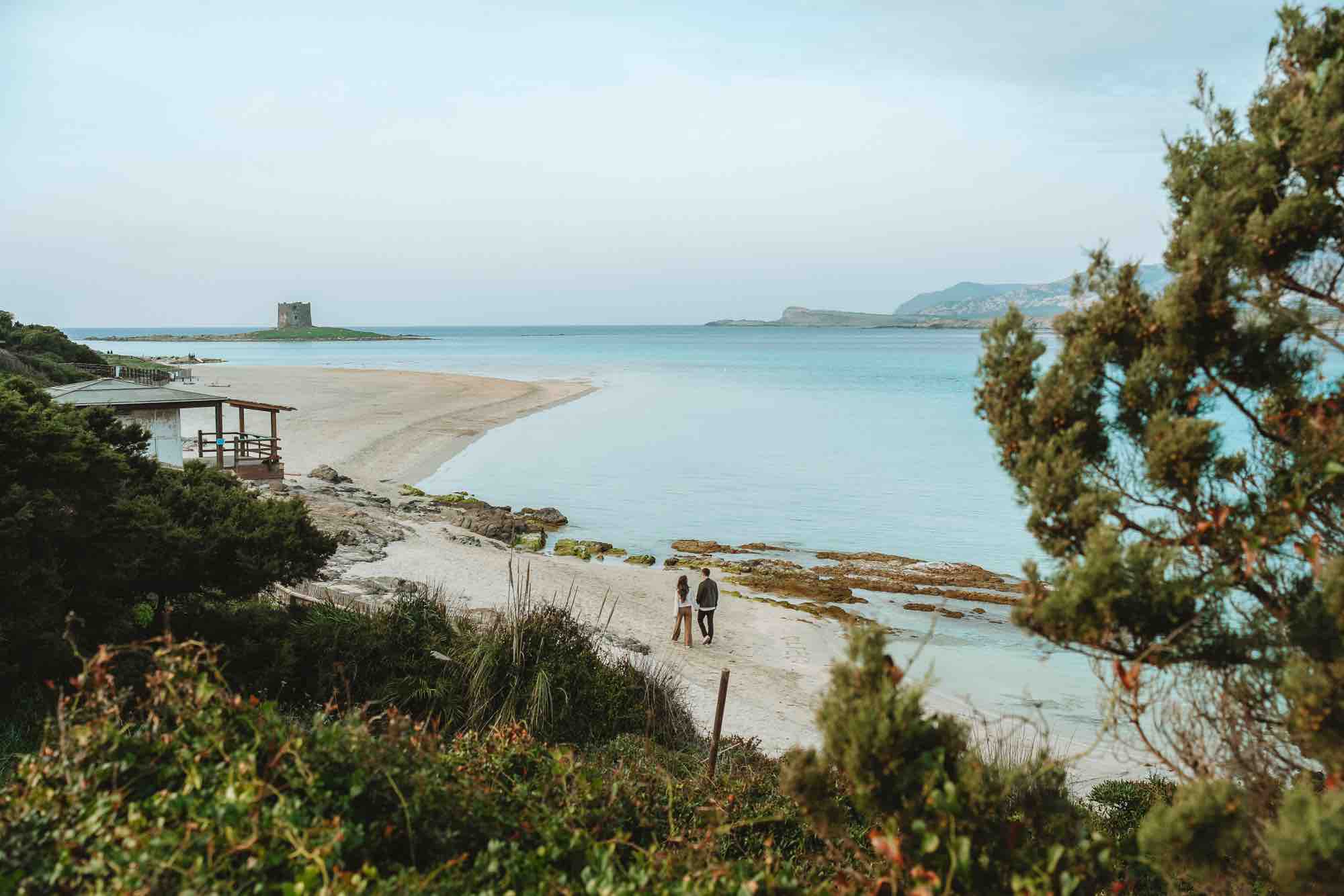 Coppia internazionale cammina sulla sabbia bianca della Pelosa durante un servizio fotografico prematrimoniale