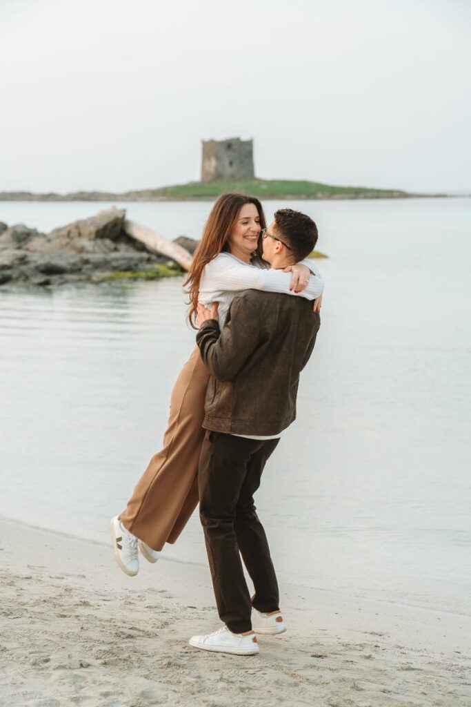 Dettaglio dell'abbraccio tra Nikkie e Doug con lo sfondo torre de La Pelosa