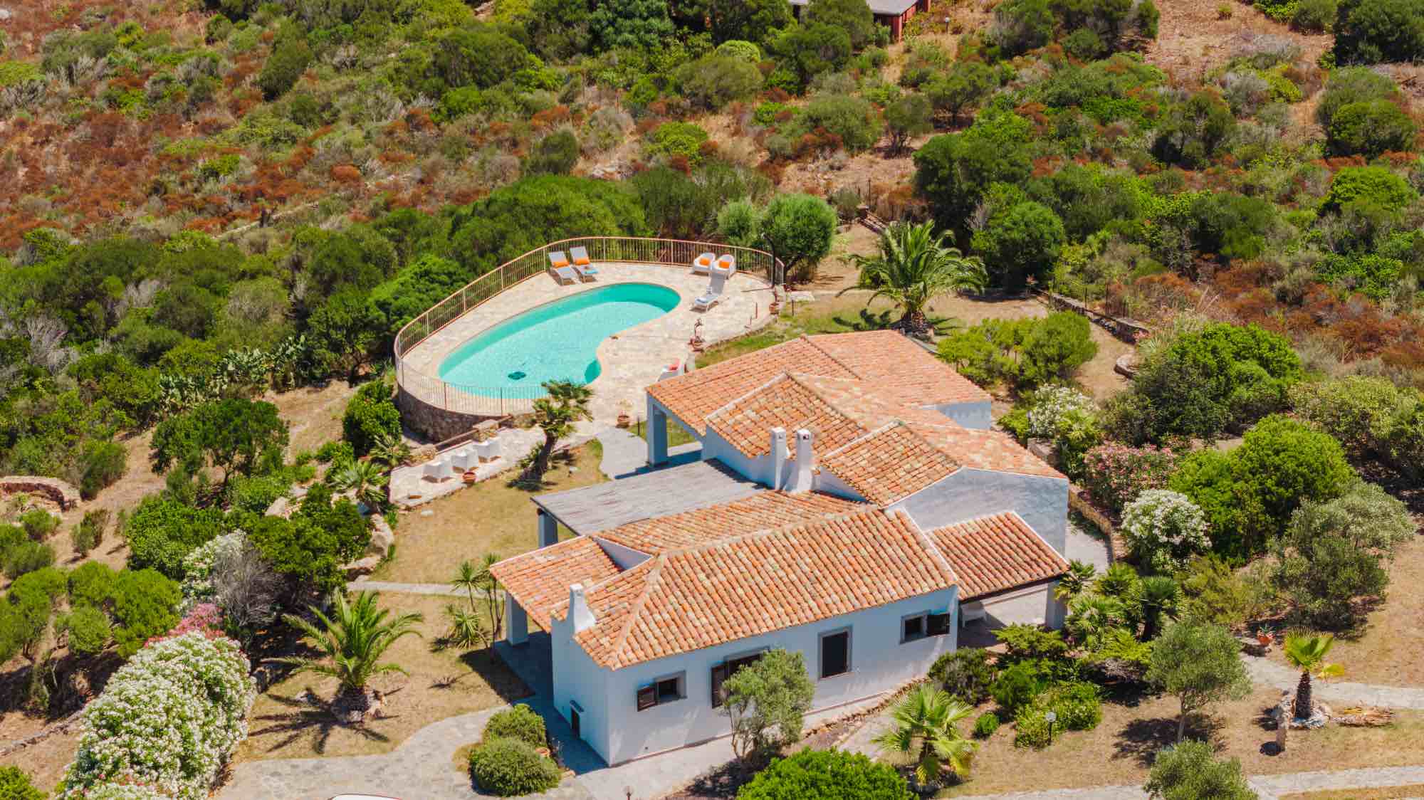 Veduta aerea di una villa in Sardegna con piscina privata a sfioro circondata dalla macchia mediterranea